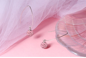 Macro shot of silver ear hooks with pink rhinestone-studded spherical crystal charms