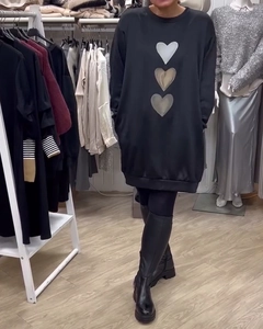 Detalle de un vestido sudadera negro con cuello redondo y diseño de tres corazones