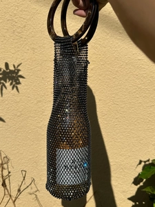 Detailed view of handmade black mesh wine bottle bag with sparkling rhinestone accents