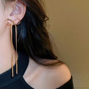 Vue détaillée de longues boucles d'oreilles à pampilles dorées avec un nœud