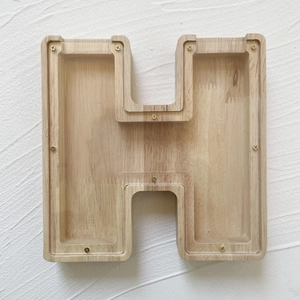 Close-up of letter H wooden money box with transparent acrylic cover and visible screws