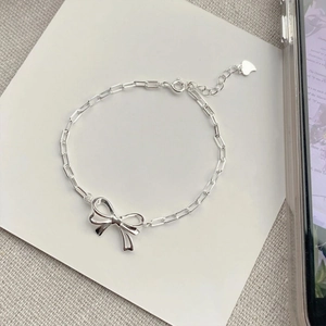 Close-up of silver bow pendant with rectangular chain links and heart charm detail