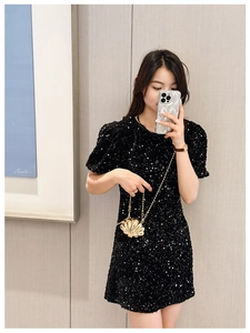 Chic gold shell-shaped mini handbag paired with a black sequin dress for a modern look