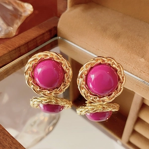 Detailed macro shot of vintage gold-wrapped magenta resin earrings with cable chain edges
