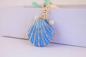 Macro shot of blue seashell keychain with rows of rhinestones and white pearls detail