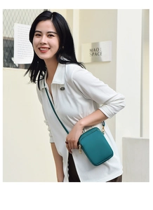 Deep peacock blue nylon mobile phone crossbody bag shown on a female model