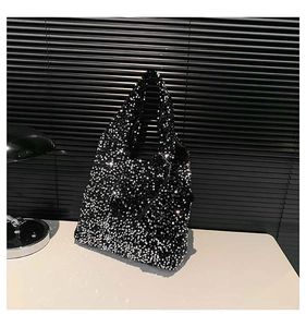 Close-up of black sequined tote bag with matching mini coin purse on white surface