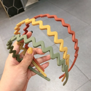 Close-up of wavy matte resin headbands in rust red, mustard yellow, and olive green