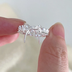 Gros plan d'une bague nœud en argent avec détails métalliques texturés et design ouvert