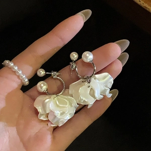Dettaglio di orecchini floreali con petali di madreperla bianca e perle finte