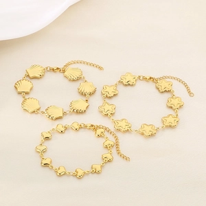 Detailed view of three gold-plated bracelets with shell, star, and heart charms on a texture