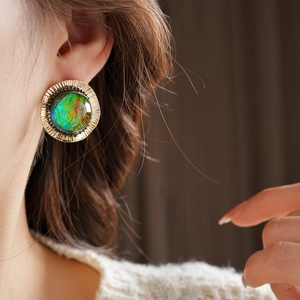 Close-up of vintage gold textured round earrings with vibrant colorful resin inlays