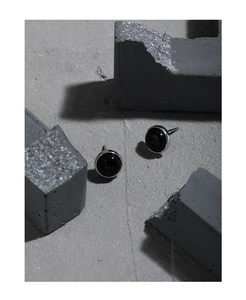 Detailed view of minimalist S925 silver stud earrings with black onyx on concrete