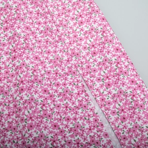 Detailed close-up of pink floral fabric stitching and printed pattern texture on dress