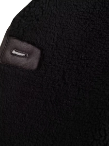 Détail du tissu en peau de mouton noire avec empiècement en cuir marron et coutures