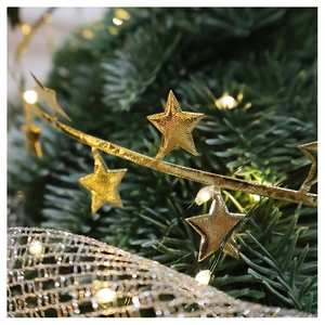 Close-up of golden star Christmas garland with festive bokeh background and tree