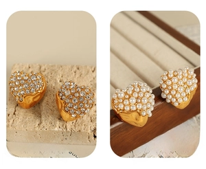 Macro detail of heart-shaped gold earrings with lava texture, pearls and crystals