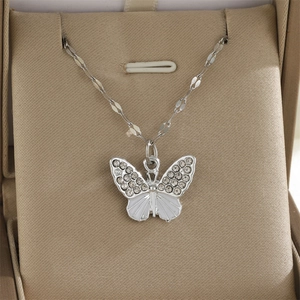 Détail d'un pendentif papillon argenté avec strass brillants et émail blanc élégant
