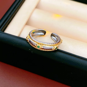 Detailed close-up of vintage oval open ring with green stones in black jewelry box
