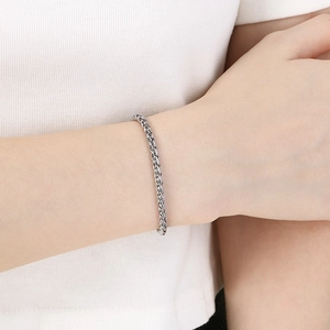 Gros plan d'un bracelet gourmette en acier inoxydable argenté au poignet féminin