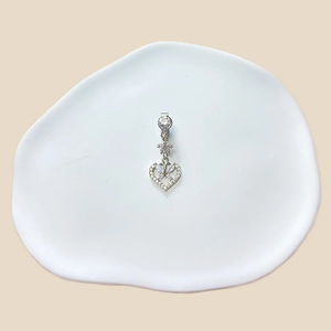 Macro shot of silver heart and butterfly navel ring with sparkling crystals on ceramic tray