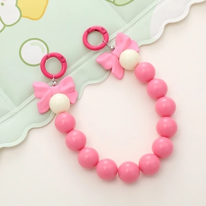 Detail view of pink and cream acrylic beaded strap with bow accents and metal spring buckles
