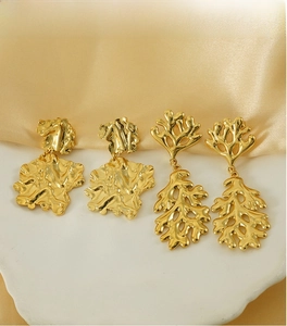 Detail of two pairs of 18K gold leaf earrings on elegant satin and stone display