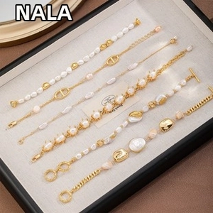 Detailed view of six Baroque pearl and gold metal bracelets on a beige linen tray
