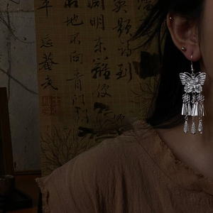 Detail of silver hollow butterfly flower tassel earrings with bells in retro style