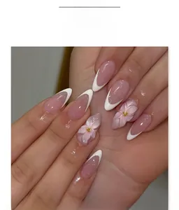 Gros plan d'ongles adhésifs French avec fleurs 3D roses et pointes blanches sur nude