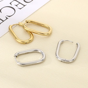 Close-up of gold and silver U-shaped stainless steel earrings with S.STEEL engraving