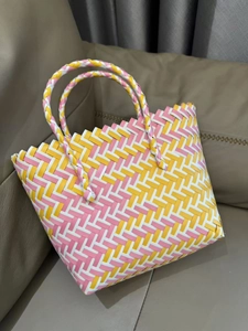 Close-up of handmade woven tote bag with pink, yellow, and white diamond patterns