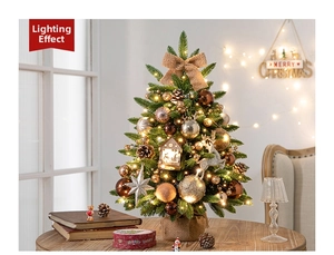 Close-up of a lit mini Christmas tree with gold baubles and warm LED lights on a table