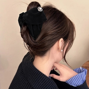 Detailed view of a black velvet bow hair claw featuring a pearl camellia metal ornament