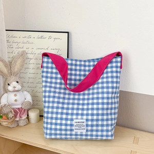 Sac fourre-tout en toile à carreaux avec bandoulière rose sur une étagère en bois