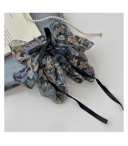 Detail of floral chiffon bow hair claw with elegant ribbons and aesthetic texture