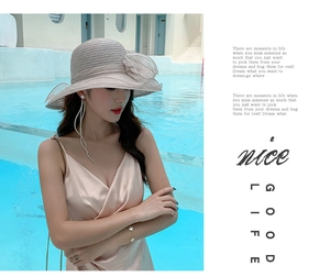 Detail of grey beach hat with organza flowers against a blue pool background