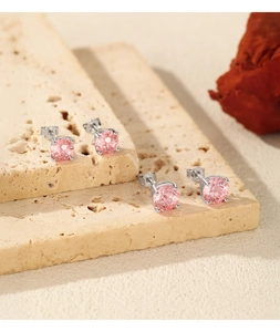 Detail of pink morganite earrings in silver four-prong setting on beige stone base