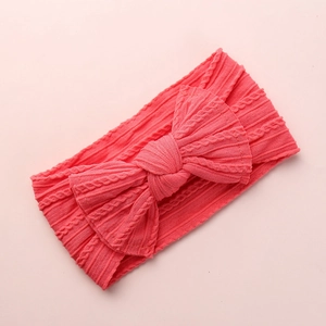 Macro detail of coral pink jacquard knit baby headband featuring a large soft bow