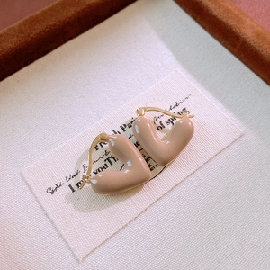 Macro detail of vintage heart huggie earring with beige enamel and golden metal base