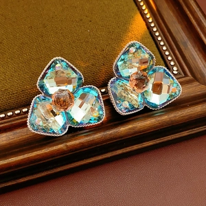 Detailed view of floral stud earrings with aurora crystals in a vintage wooden frame