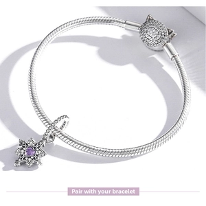 Detail of silver snake chain bracelet featuring a purple heart snowflake charm and cat clasp