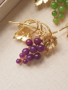 Macro shot of purple grape brooch with golden leaves and detailed metal craftsmanship