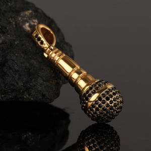 Hip hop microphone pendant in polished gold with black pave-set stones on rock surface