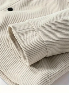 Detaillierte Nahaufnahme der beigen Cordstruktur mit schwarzem Knopf und feiner Naht