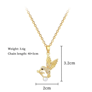 Gros plan d'un collier hirondelle doré avec diamants pavés et perle sur fond blanc