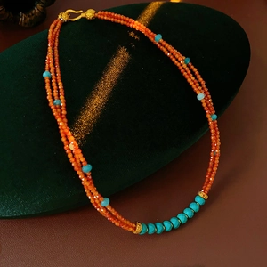 Close-up of vintage multi-layer orange and blue beaded necklace with gold metal clasp