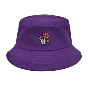 Detail of three red mushroom embroidery on a purple cotton bucket hat with clean stitching