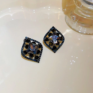 Close-up of vintage rhombic earrings with navy blue stones and black crystal accents