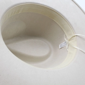Detail view of the interior sweatband and 100% polyester material label of the beige hat